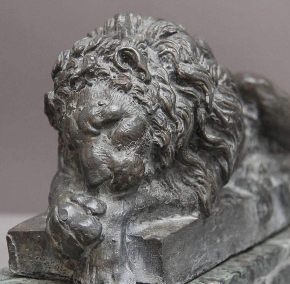 A pair of cast metal reclining lion models, one sleeping and one vigilant, mounted on rectangular green marble bases. View VIII