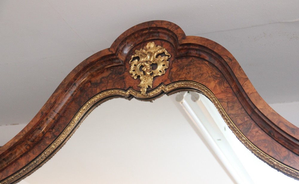 A 19th-century burr walnut credenza with an arched mirror back, ornate gilt-bronze mounts, open tier side shelving, and a central glazed compartment. View III