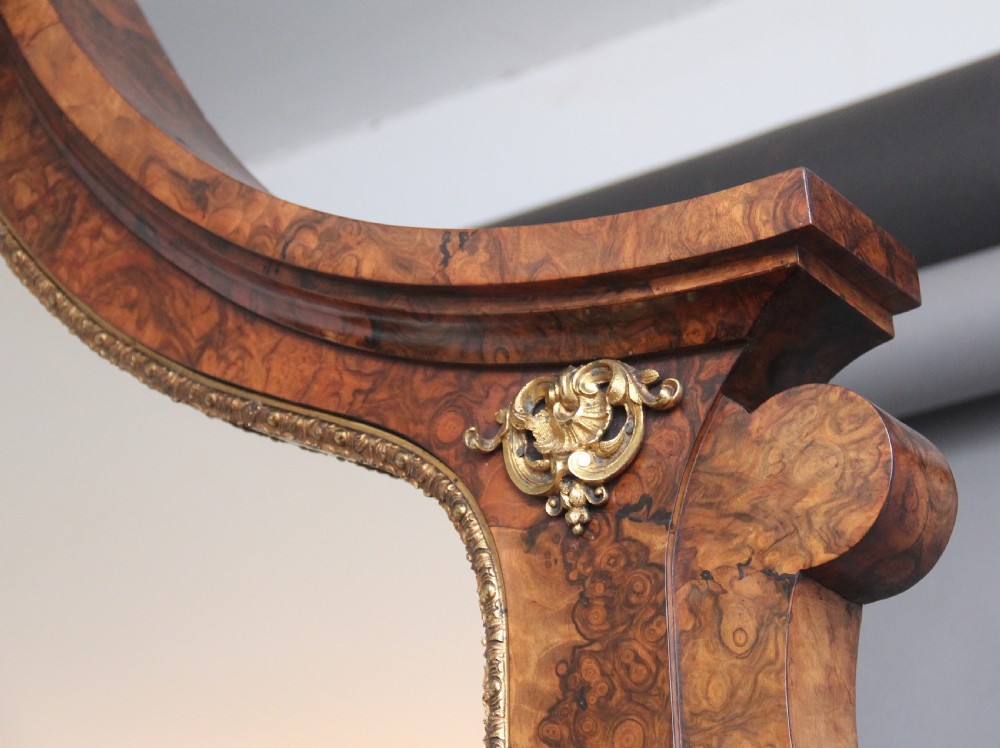 A 19th-century burr walnut credenza with an arched mirror back, ornate gilt-bronze mounts, open tier side shelving, and a central glazed compartment. View VII