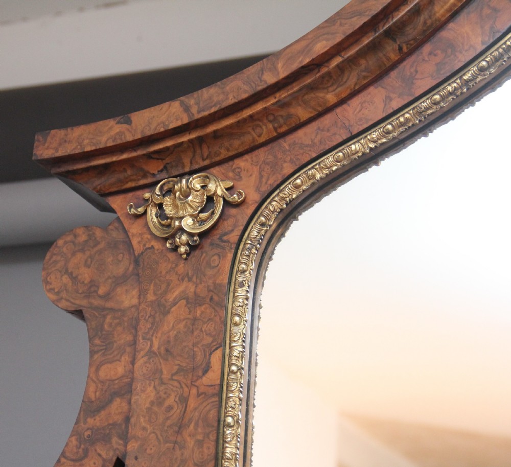 A 19th-century burr walnut credenza with an arched mirror back, ornate gilt-bronze mounts, open tier side shelving, and a central glazed compartment. View IX