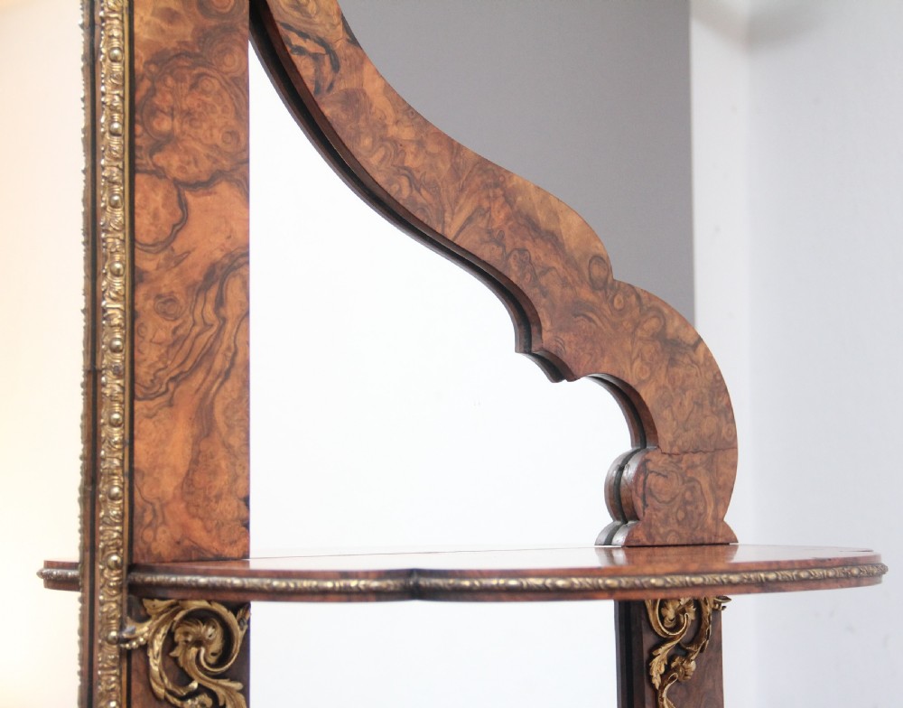 A 19th-century burr walnut credenza with an arched mirror back, ornate gilt-bronze mounts, open tier side shelving, and a central glazed compartment. View XI