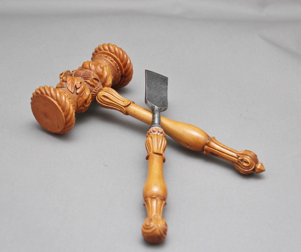 A 19th-century ceremonial set featuring an intricately hand-carved wooden mallet with foliate motifs and a matching carved wooden-handled steel chisel.