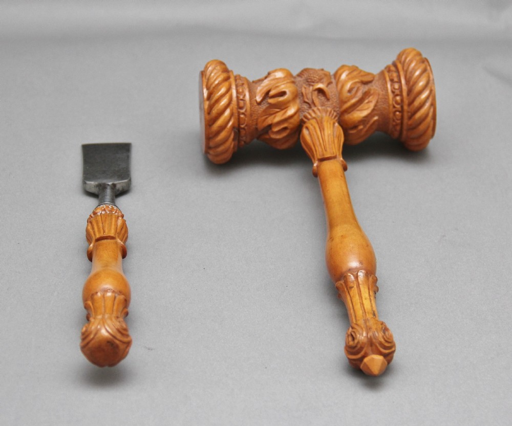 A 19th-century ceremonial set featuring an intricately hand-carved wooden mallet with foliate motifs and a matching carved wooden-handled steel chisel. View II