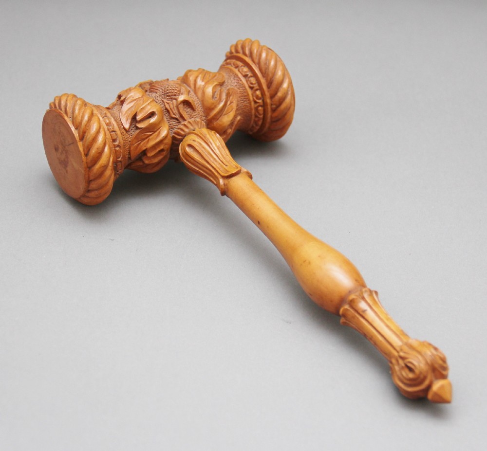 A 19th-century ceremonial set featuring an intricately hand-carved wooden mallet with foliate motifs and a matching carved wooden-handled steel chisel. View V