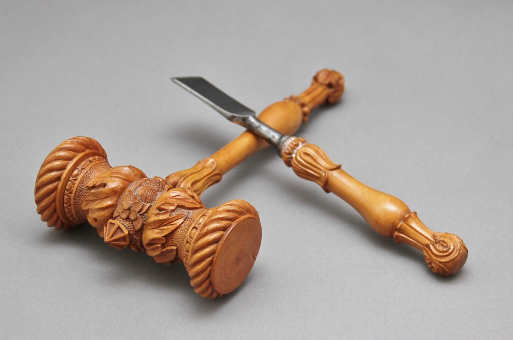 A 19th-century ceremonial set featuring an intricately hand-carved wooden mallet with foliate motifs and a matching carved wooden-handled steel chisel. View VII