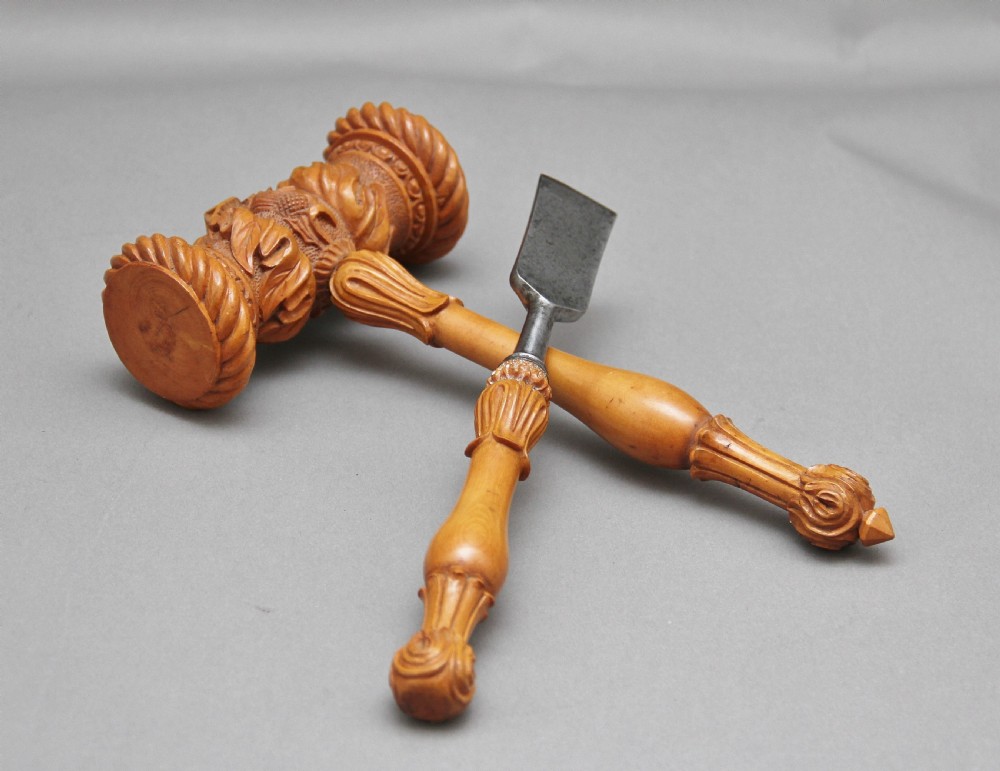 A 19th-century ceremonial set featuring an intricately hand-carved wooden mallet with foliate motifs and a matching carved wooden-handled steel chisel. View IX