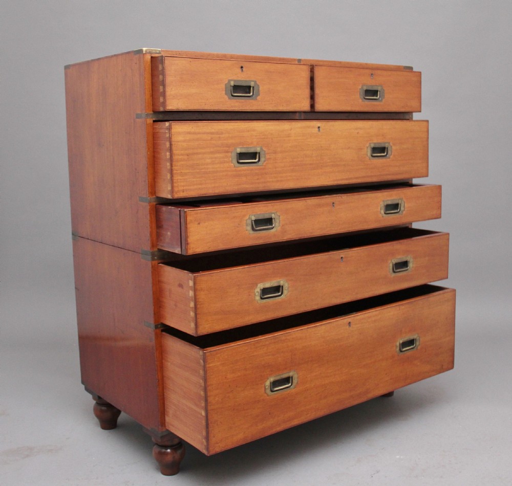 A nineteenth-century mahogany military secretaire chest in two sections with brass corners, flush brass handles, turned feet, and an extended writing drawer. View IV