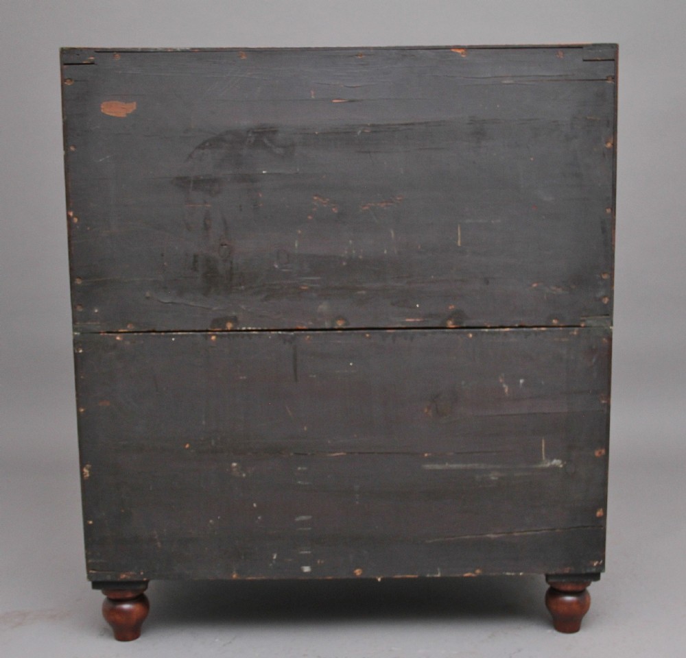 A nineteenth-century mahogany military secretaire chest in two sections with brass corners, flush brass handles, turned feet, and an extended writing drawer. View VI