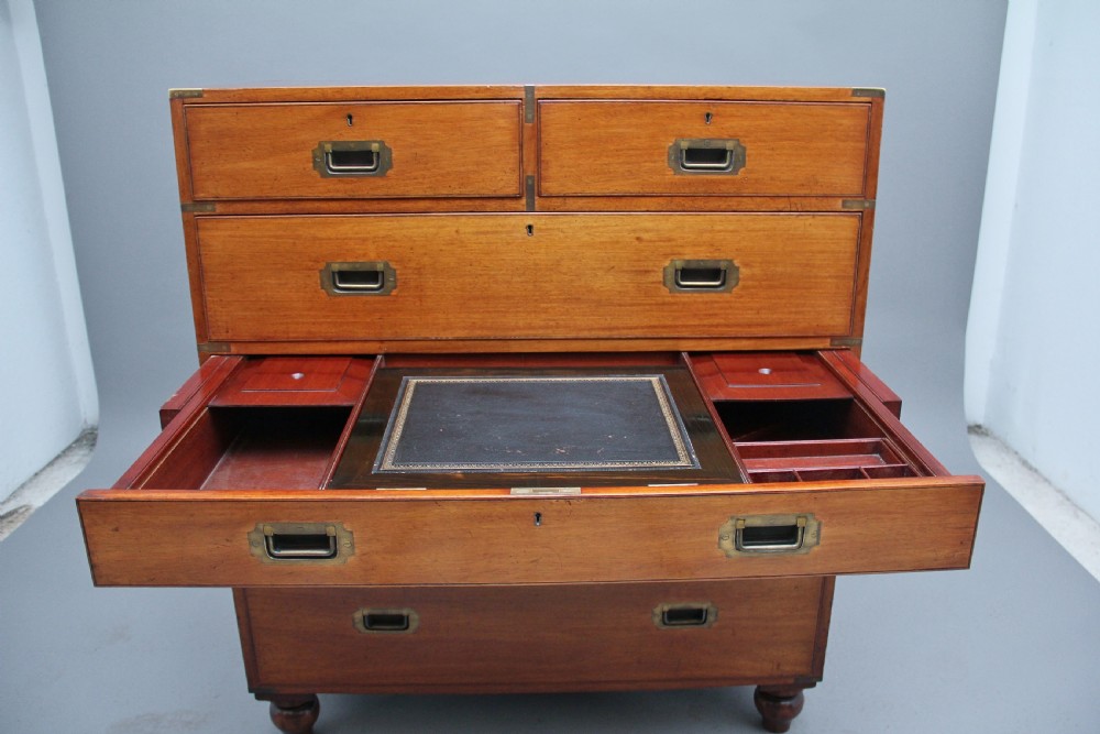 A nineteenth-century mahogany military secretaire chest in two sections with brass corners, flush brass handles, turned feet, and an extended writing drawer. View X