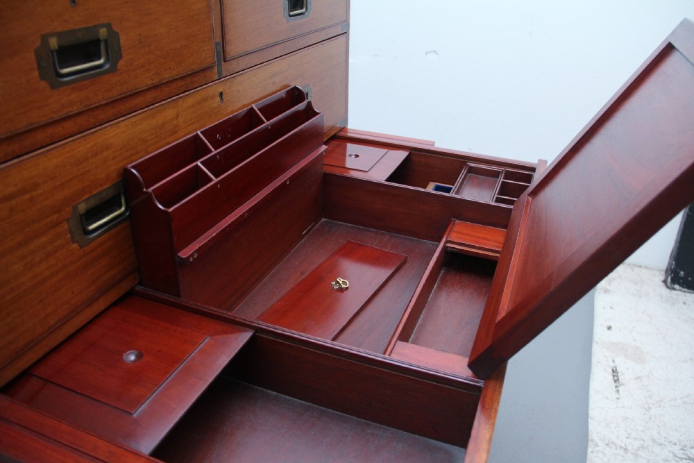 A nineteenth-century mahogany military secretaire chest in two sections with brass corners, flush brass handles, turned feet, and an extended writing drawer. View XIV