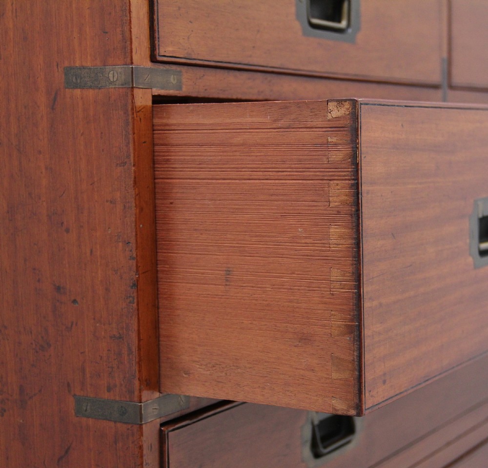 A nineteenth-century mahogany military secretaire chest in two sections with brass corners, flush brass handles, turned feet, and an extended writing drawer. View XVII
