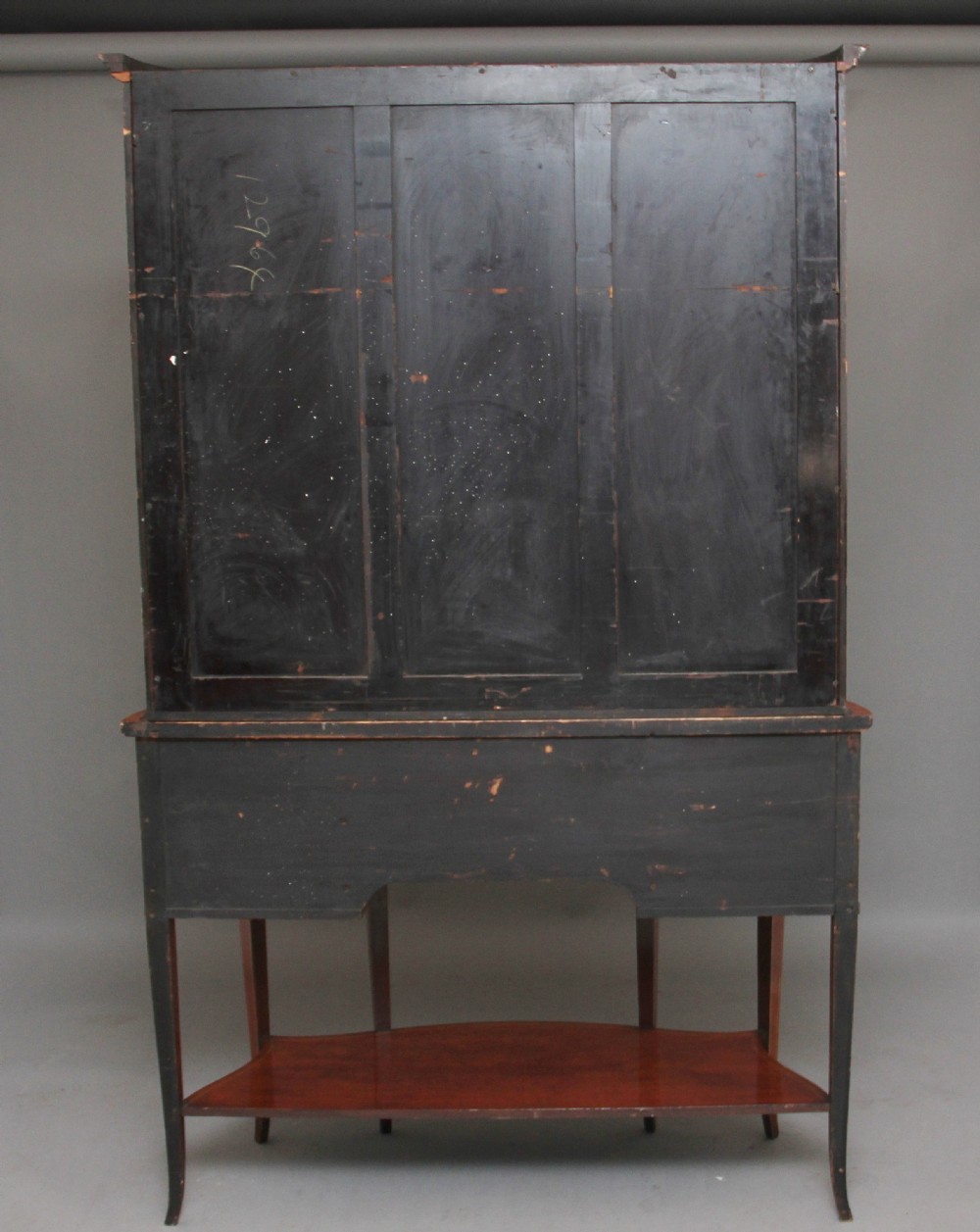 A late 19th-century bow-fronted mahogany display cabinet featuring glazed doors, satinwood marquetry inlay, slender square legs, and an undertier. View IX