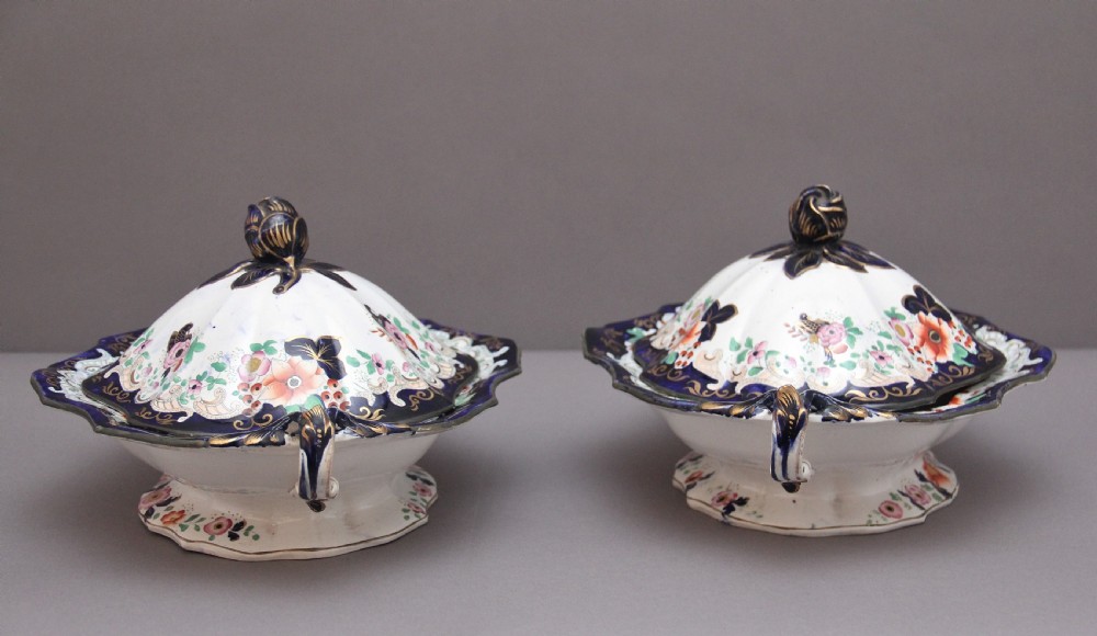 A pair of 19th-century white and cobalt blue ironstone tureens featuring hand-painted floral decoration, gilt accents, moulded handles, and flower bud finials. View V
