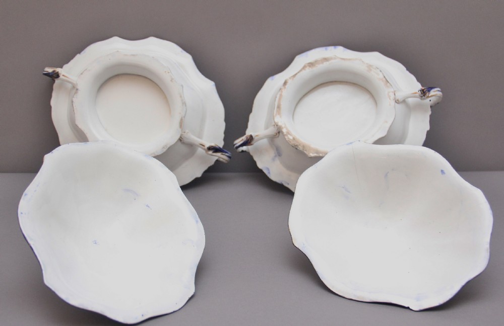 A pair of 19th-century white and cobalt blue ironstone tureens featuring hand-painted floral decoration, gilt accents, moulded handles, and flower bud finials. View X