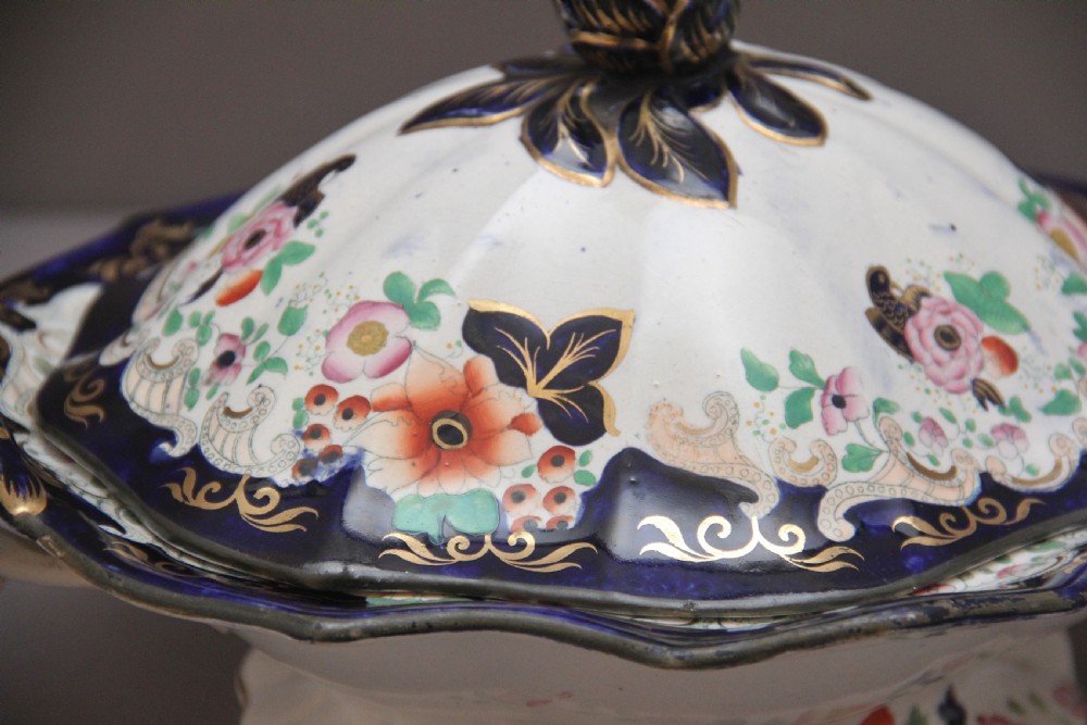 A pair of 19th-century white and cobalt blue ironstone tureens featuring hand-painted floral decoration, gilt accents, moulded handles, and flower bud finials. View XI