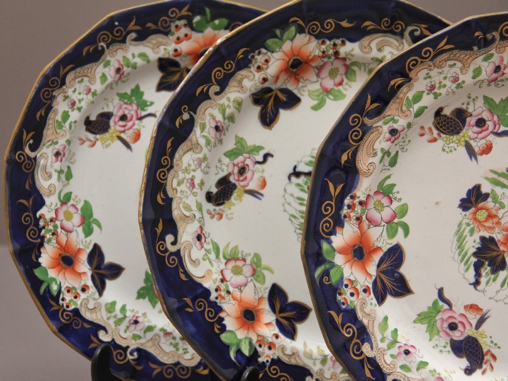 A set of six octagonal 19th-century Masons ironstone plates featuring cobalt blue borders, orange and pink floral transfer motifs, and gilt highlights. View IV