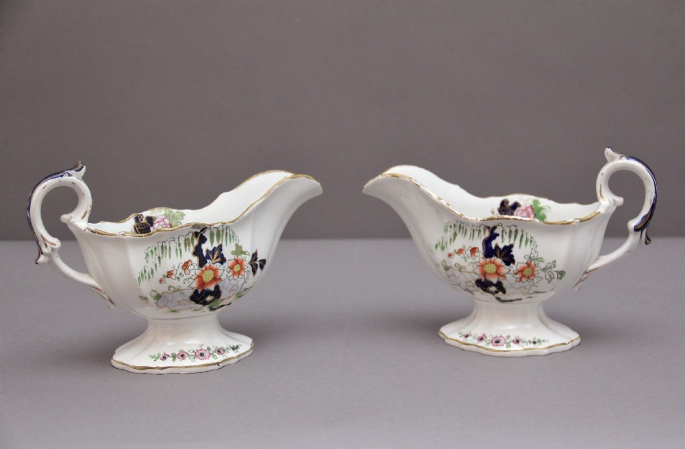 A pair of early nineteenth-century white porcelain sauceboats decorated with hand-painted floral motifs, cobalt blue accents, and gilded scalloped rims.