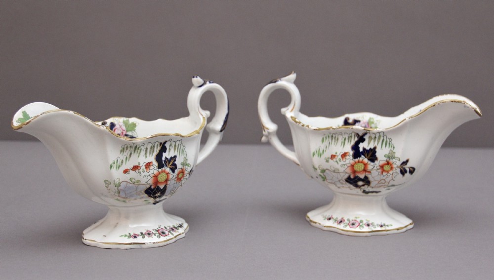 A pair of early nineteenth-century white porcelain sauceboats decorated with hand-painted floral motifs, cobalt blue accents, and gilded scalloped rims. View V