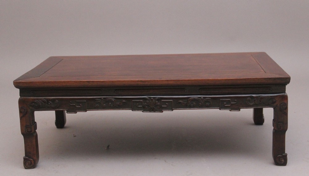 A 19th-century Chinese carved dark wood low table with a floating panel top and stylized scroll feet. View II