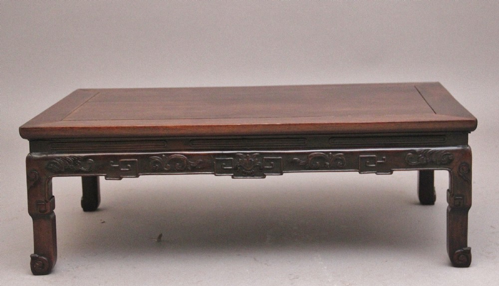A 19th-century Chinese carved dark wood low table with a floating panel top and stylized scroll feet. View V