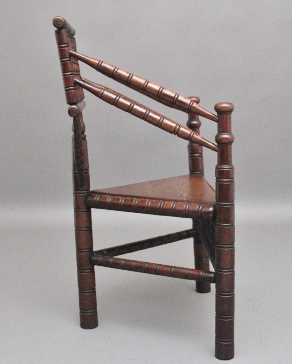 A 19th-century dark oak turners chair featuring a triangular seat, intricate bobbin-turned backrest, and sturdy turned wooden legs. View III