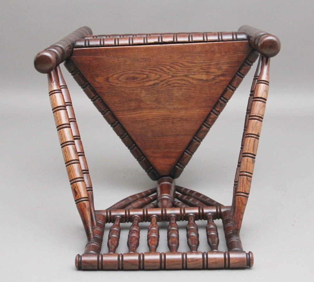 A 19th-century dark oak turners chair featuring a triangular seat, intricate bobbin-turned backrest, and sturdy turned wooden legs. View V