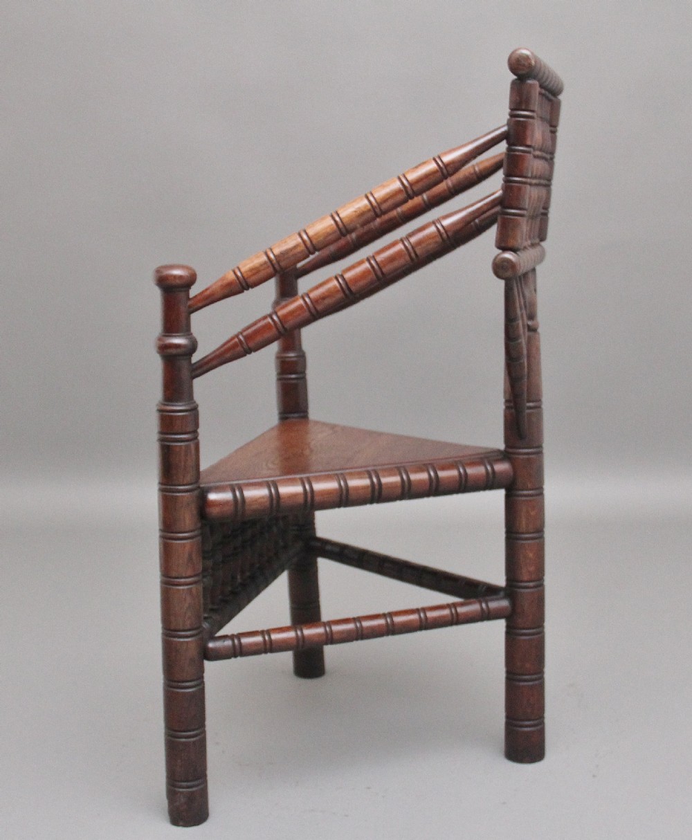 A 19th-century dark oak turners chair featuring a triangular seat, intricate bobbin-turned backrest, and sturdy turned wooden legs. View VI