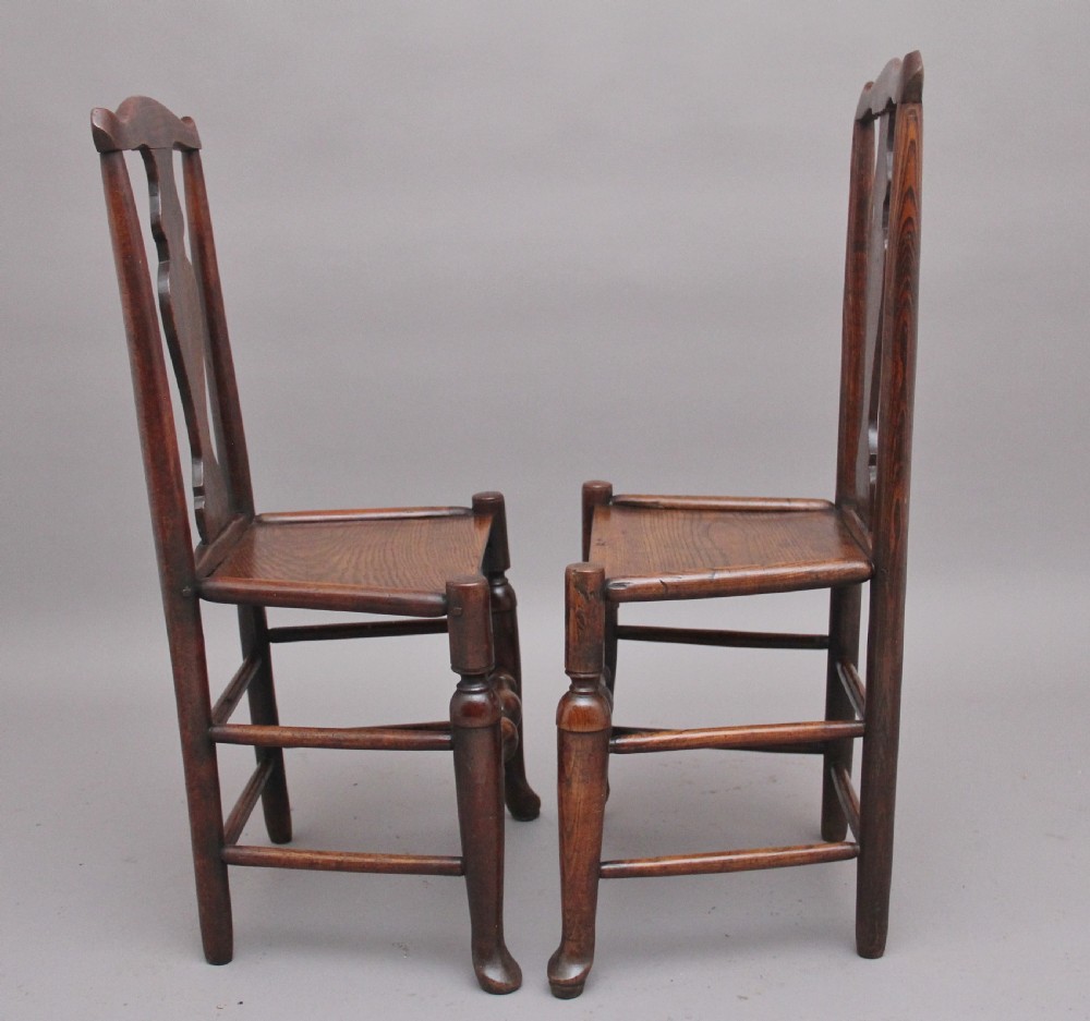 A pair of 18th-century elm side chairs featuring shaped top rails, vasiform back splats, solid wooden seats, and turned front legs with stretchers. View III