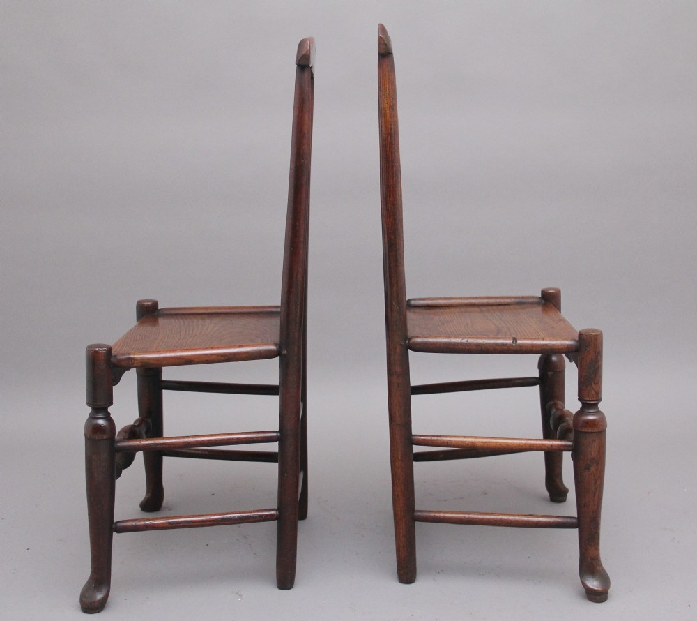 A pair of 18th-century elm side chairs featuring shaped top rails, vasiform back splats, solid wooden seats, and turned front legs with stretchers. View V