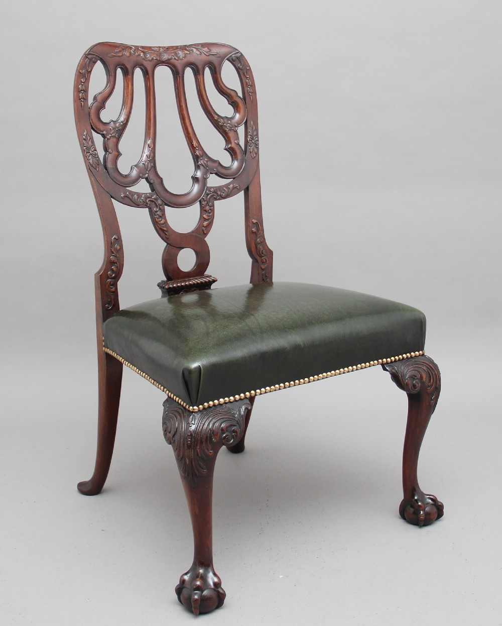 A pair of 19th-century mahogany side chairs featuring pierced carved splats, green leather seats with brass studs, and cabriole legs with ball-and-claw feet. View IV