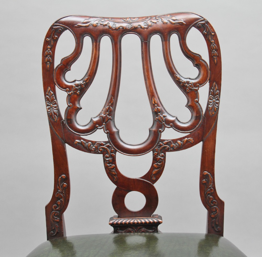 A pair of 19th-century mahogany side chairs featuring pierced carved splats, green leather seats with brass studs, and cabriole legs with ball-and-claw feet. View V