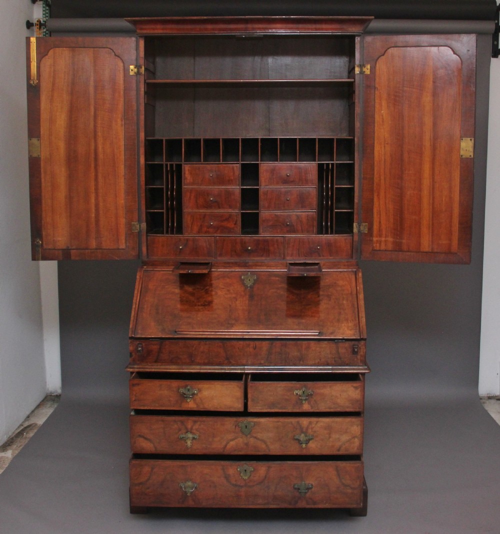 An early 18th-century walnut bureau bookcase featuring a slant-front writing desk base over drawers and an upper cabinet with two mirrored doors. View IV