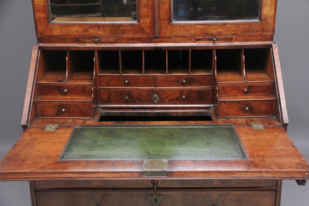 An early 18th-century walnut bureau bookcase featuring a slant-front writing desk base over drawers and an upper cabinet with two mirrored doors. View V