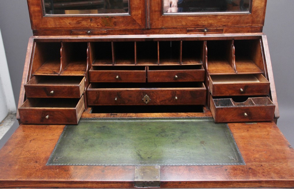 An early 18th-century walnut bureau bookcase featuring a slant-front writing desk base over drawers and an upper cabinet with two mirrored doors. View VI