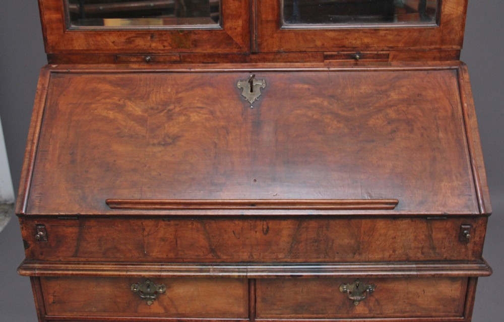 An early 18th-century walnut bureau bookcase featuring a slant-front writing desk base over drawers and an upper cabinet with two mirrored doors. View VIII
