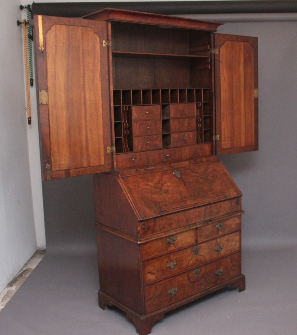 An early 18th-century walnut bureau bookcase featuring a slant-front writing desk base over drawers and an upper cabinet with two mirrored doors. View XII