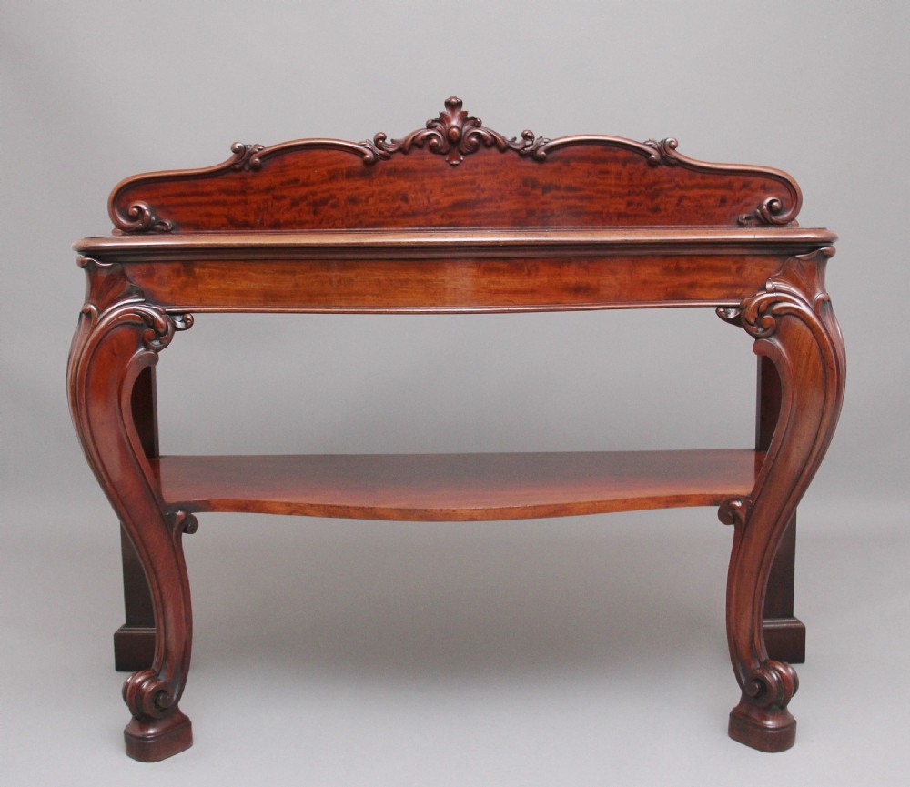 A 19th-century mahogany serving table featuring a carved back gallery, curved cabriole legs, and a lower tier shelf.