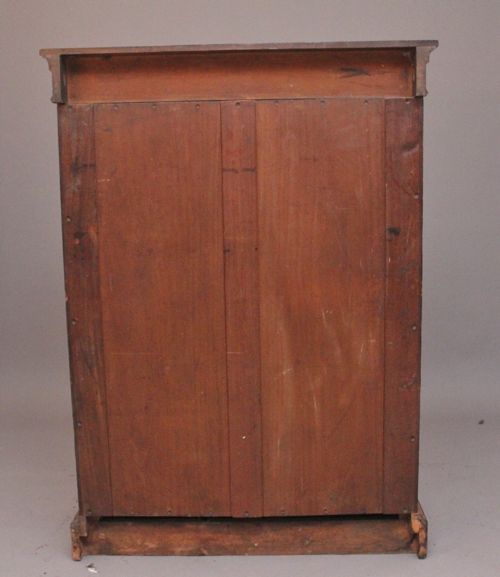A Victorian burr walnut glazed cabinet featuring an arched glass door, carved corbels, three internal shelves, and a solid plinth base. View VI