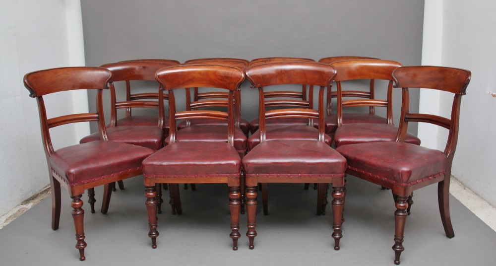 A set of twelve nineteenth-century mahogany dining chairs featuring curved top rails, turned front legs, and red leather upholstered seats with studding.