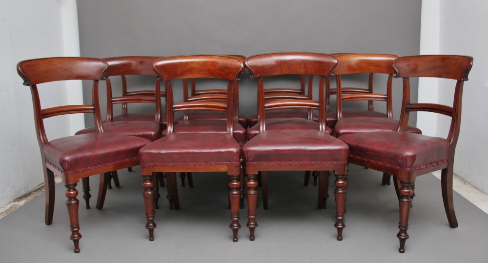 A set of twelve nineteenth-century mahogany dining chairs featuring curved top rails, turned front legs, and red leather upholstered seats with studding. View II