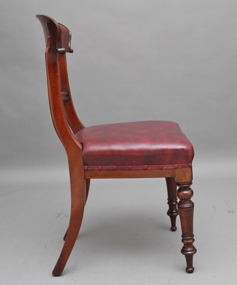 A set of twelve nineteenth-century mahogany dining chairs featuring curved top rails, turned front legs, and red leather upholstered seats with studding. View IV