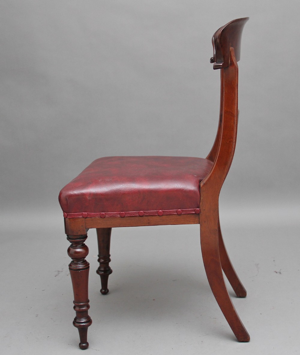 A set of twelve nineteenth-century mahogany dining chairs featuring curved top rails, turned front legs, and red leather upholstered seats with studding. View V