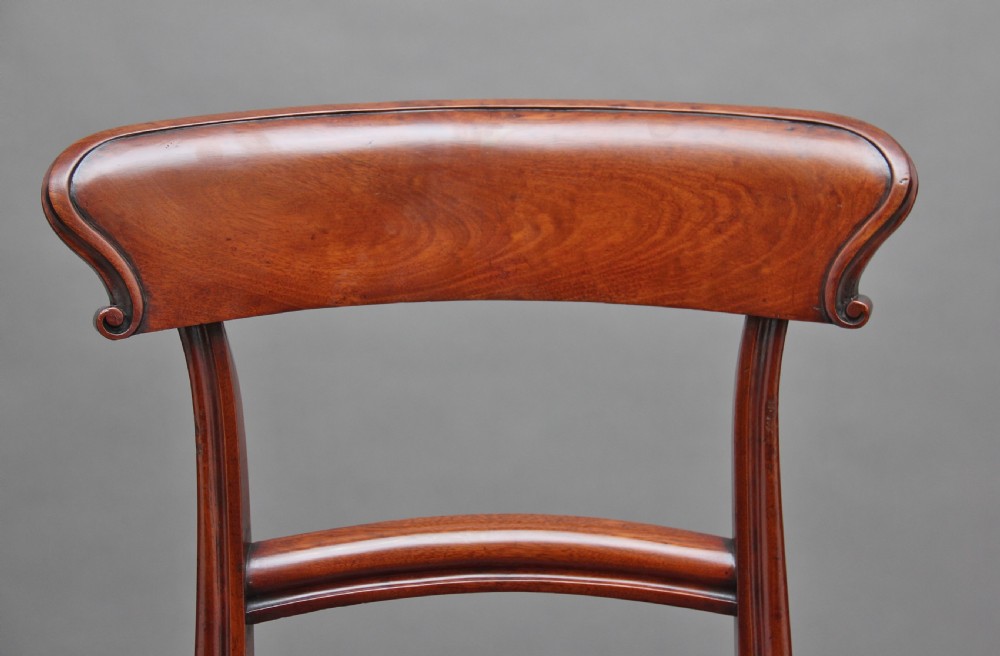 A set of twelve nineteenth-century mahogany dining chairs featuring curved top rails, turned front legs, and red leather upholstered seats with studding. View IX