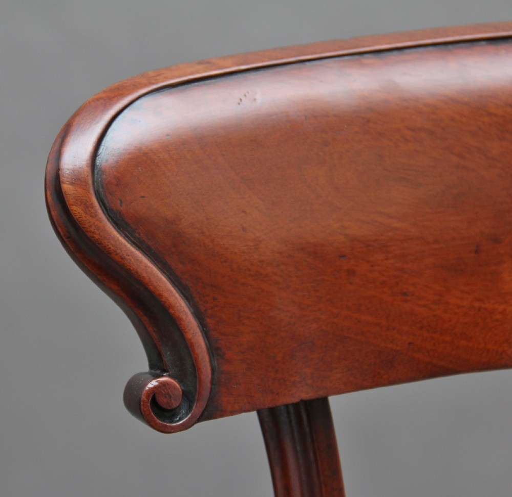 A set of twelve nineteenth-century mahogany dining chairs featuring curved top rails, turned front legs, and red leather upholstered seats with studding. View X