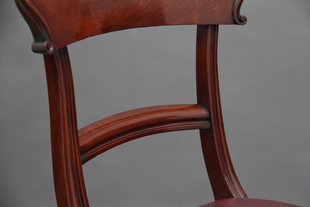 A set of twelve nineteenth-century mahogany dining chairs featuring curved top rails, turned front legs, and red leather upholstered seats with studding. View XII