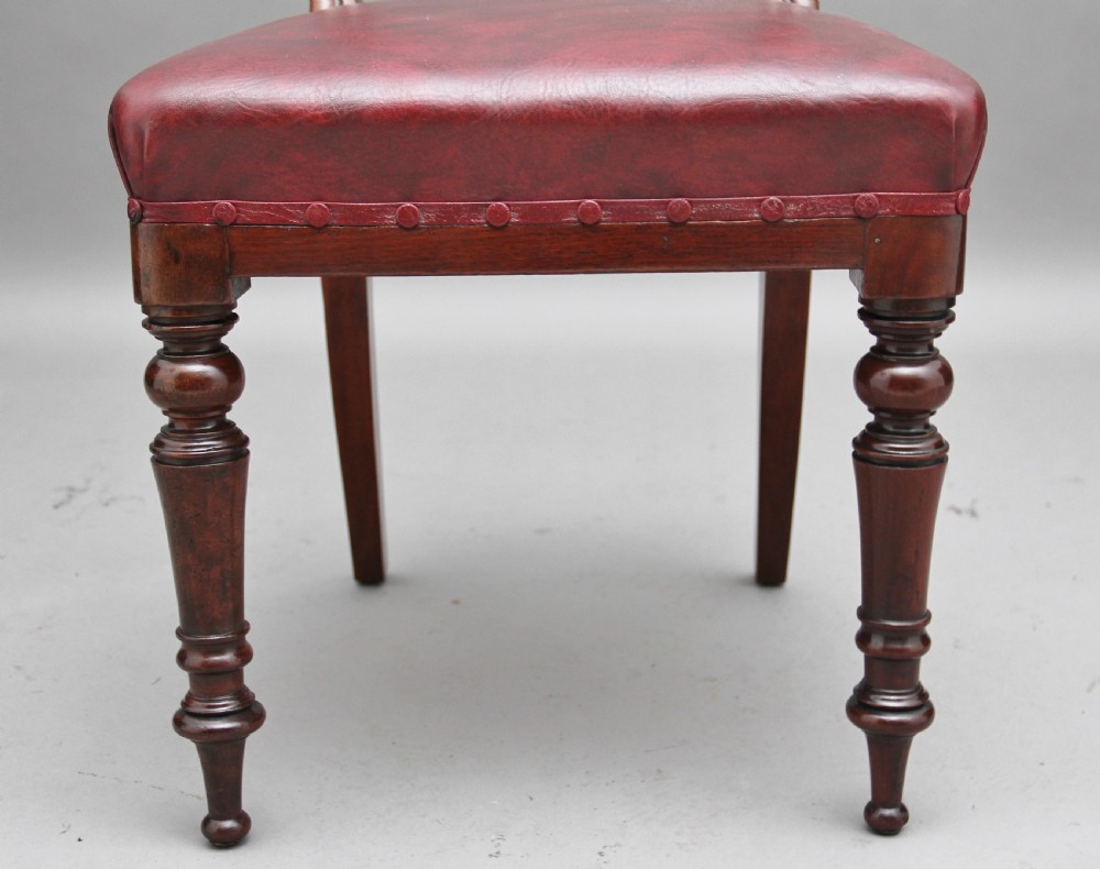 A set of twelve nineteenth-century mahogany dining chairs featuring curved top rails, turned front legs, and red leather upholstered seats with studding. View XIII