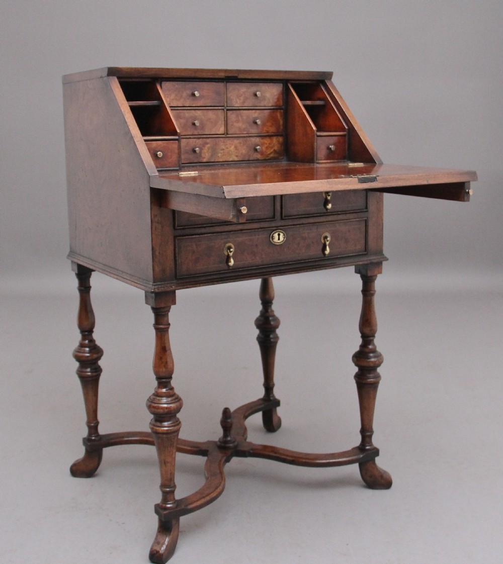 An early 20th-century walnut writing bureau on stand with a sloped fall front, lower drawers, and turned legs with a shaped cross-stretcher. View II
