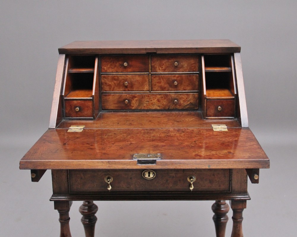 An early 20th-century walnut writing bureau on stand with a sloped fall front, lower drawers, and turned legs with a shaped cross-stretcher. View V