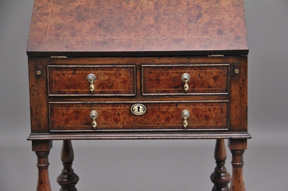 An early 20th-century walnut writing bureau on stand with a sloped fall front, lower drawers, and turned legs with a shaped cross-stretcher. View VII