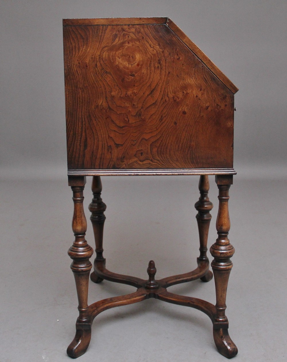 An early 20th-century walnut writing bureau on stand with a sloped fall front, lower drawers, and turned legs with a shaped cross-stretcher. View VIII